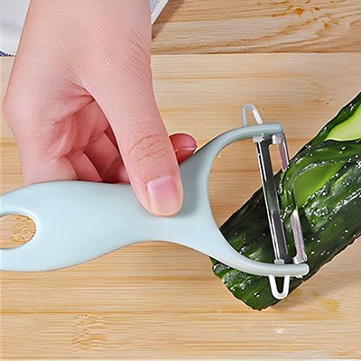 Eplucheur bleu épluchant concombre sur table en bois