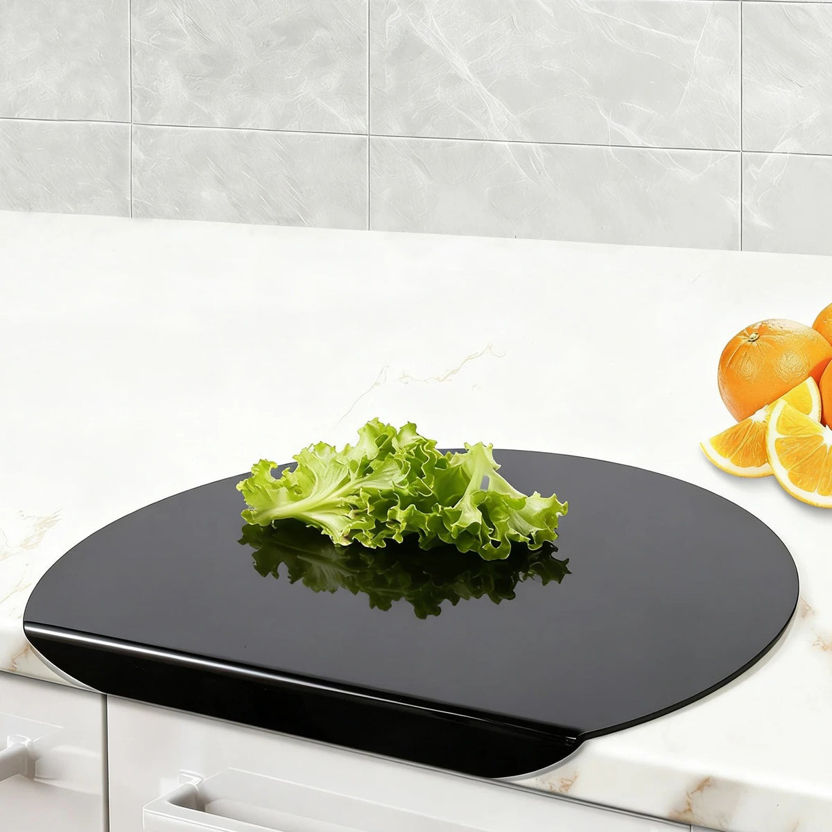 Planche a decouper avec rebord noir sur comptoir en mabre avec salade a cote dorange coupe