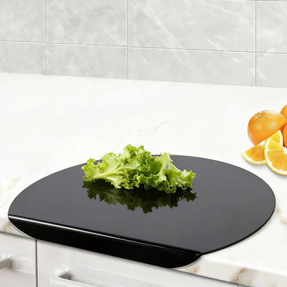 Planche a decouper avec rebord noir sur comptoir en mabre avec salade a cote dorange coupe