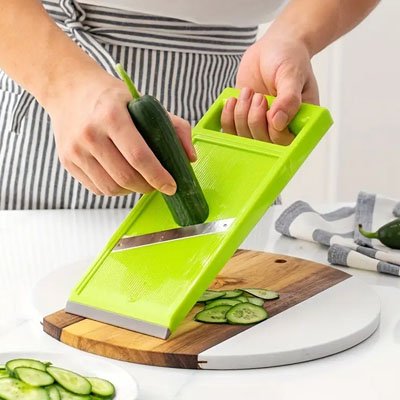Cuisine Mandoline vert coupe concombre audessus planche a découper circulaire