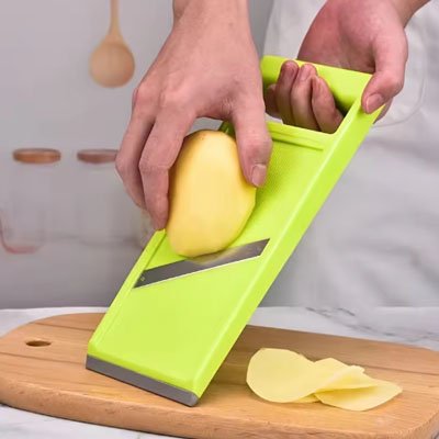 Cuisine Mandoline vert sur planche en bois pour couper pomme de trre