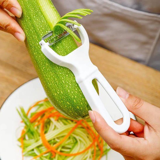 Econome blanc ergonomique râpant courgette au dessus d'un bol de légume haché