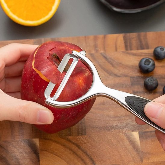 Epluche legume epluchant pomme rouge sur planche a découper avec bleuet