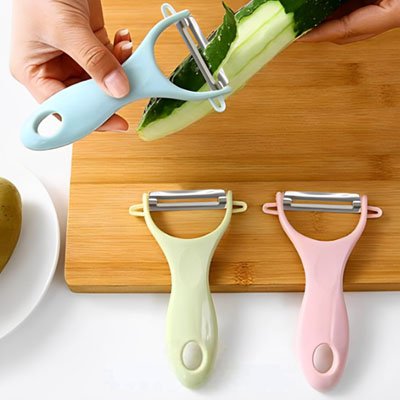 Eplucheur vert et rose posé sur planche à découper en bois