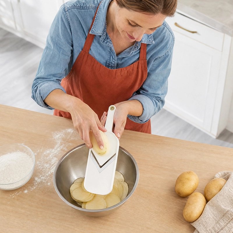 Femme en tablier rouge coupant pomme de terre avec Mandoline Cuisine lame en V