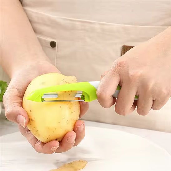 Main épluchant pomme de terre avec Econome vert